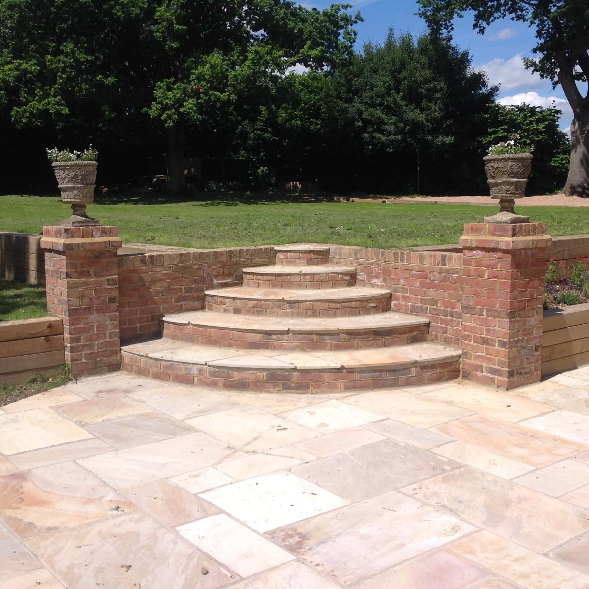 Curved brick steps with sandstone treads and stone urns